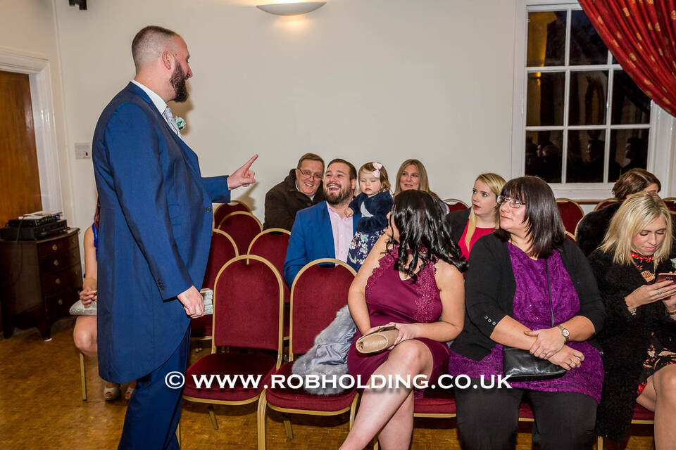 Groom speaking to seated guests indoors