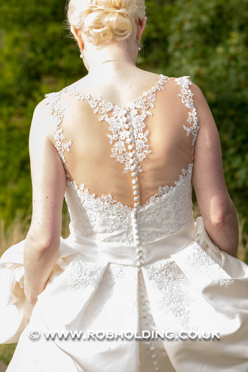Back detail of the bride’s lace wedding dress outdoors