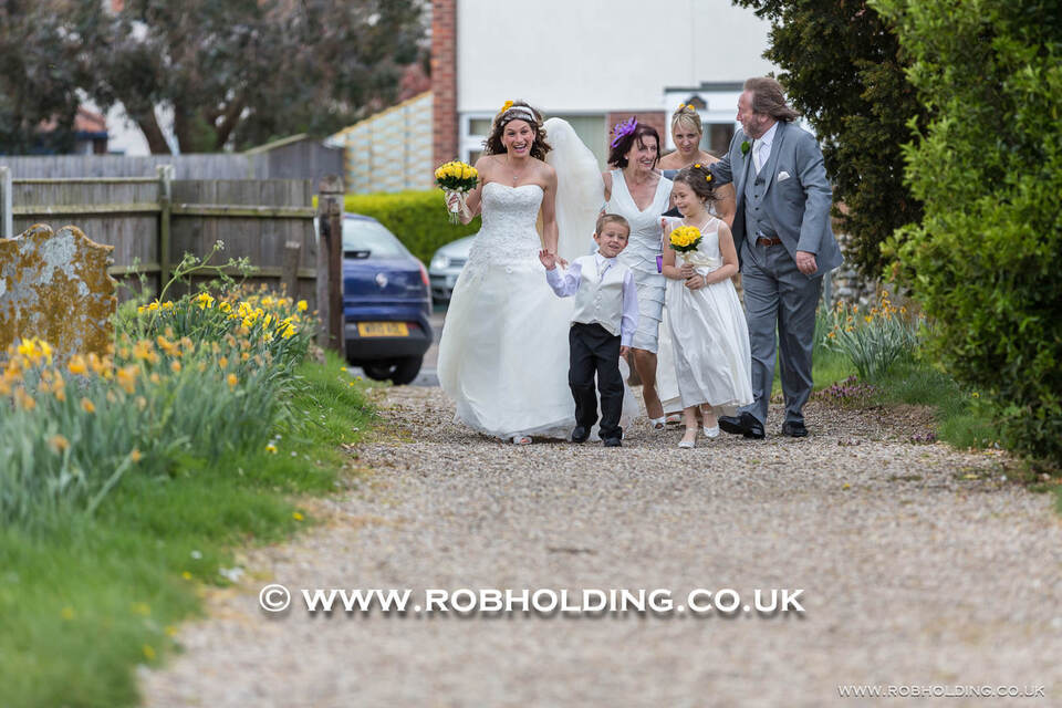 Bride and groom walking a gravel path with two young children