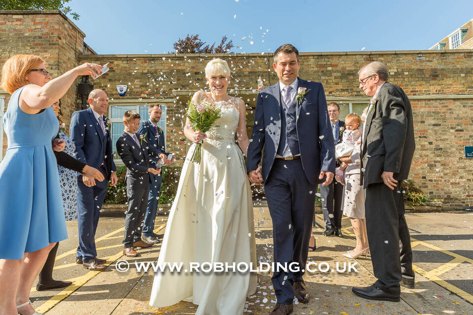 Bride and groom walking outdoors as guests blow bubbles