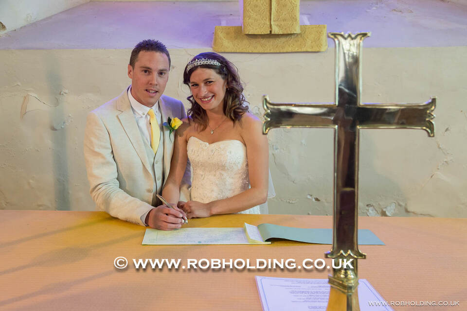Bride and groom signing the register beside a wooden cross