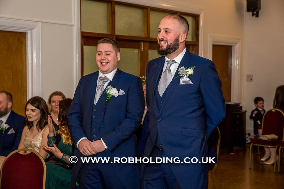Two men in navy suits smiling together at the reception