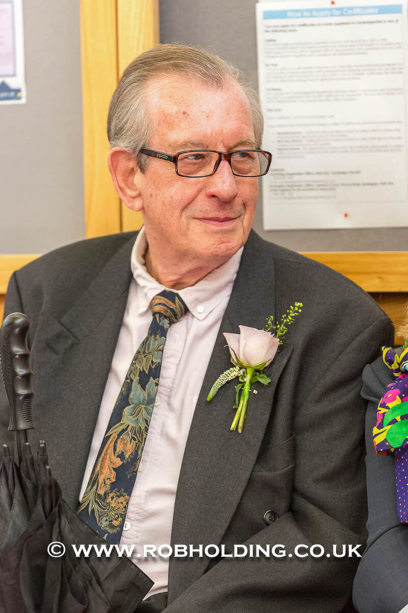 Portrait of an older man in a grey suit with a floral boutonniere