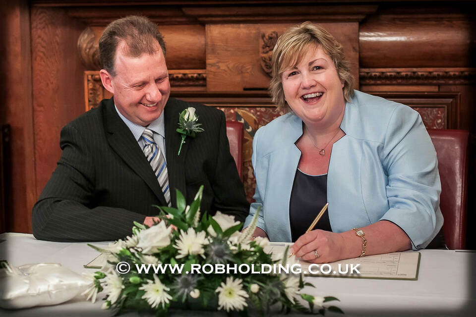 Bride and groom laughing while signing the register