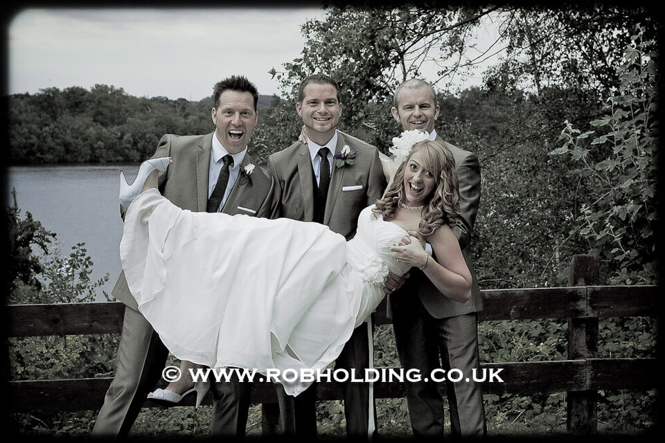 Groomsmen playfully carrying the bride, black-and-white photo