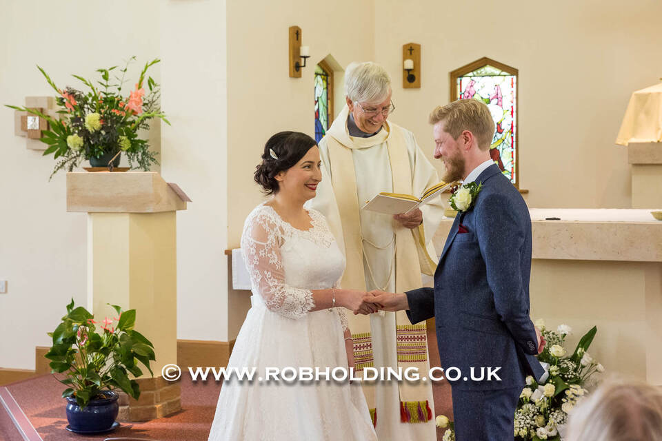 Bride and groom holding hands at the altar with the officiant