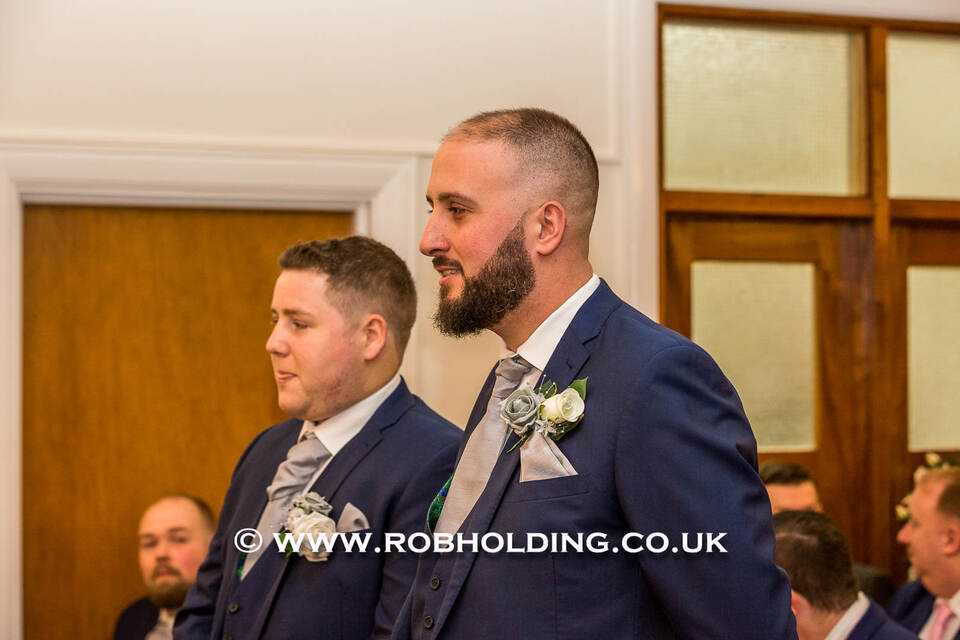 Two groomsmen laughing together during the ceremony
