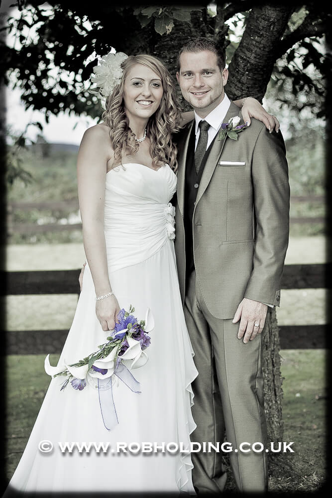 Black-and-white portrait of bride and groom under a tree