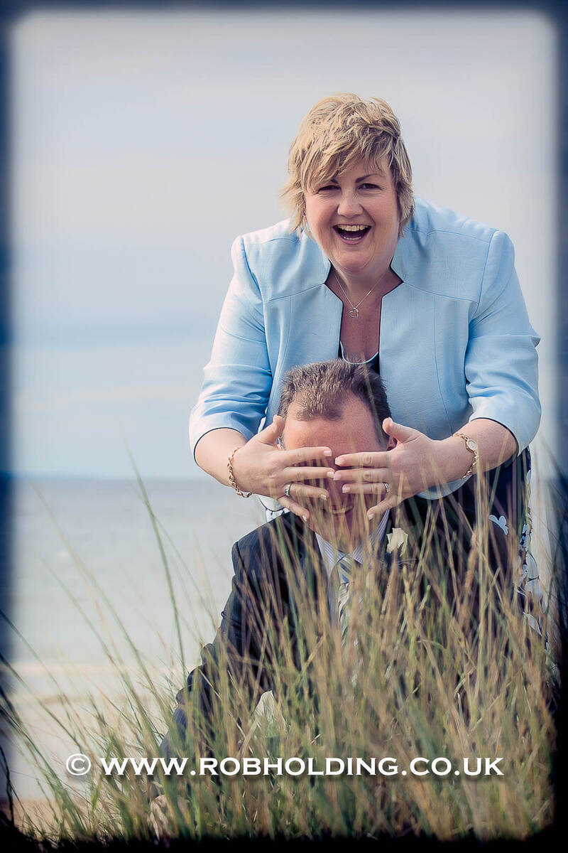 Playful candid photo of a couple in coastal grass dunes