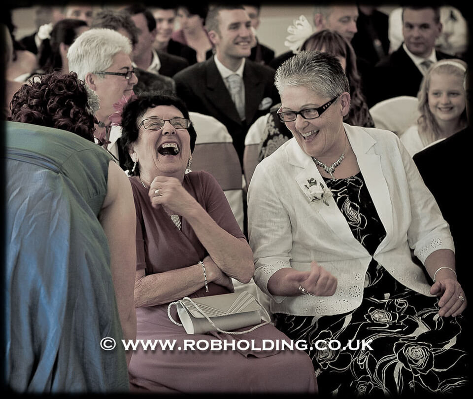 Two wedding guests laughing together during the ceremony