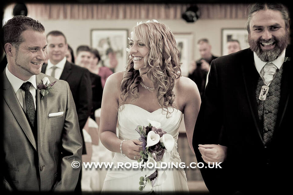 Bride, groom and best man laughing together at the ceremony