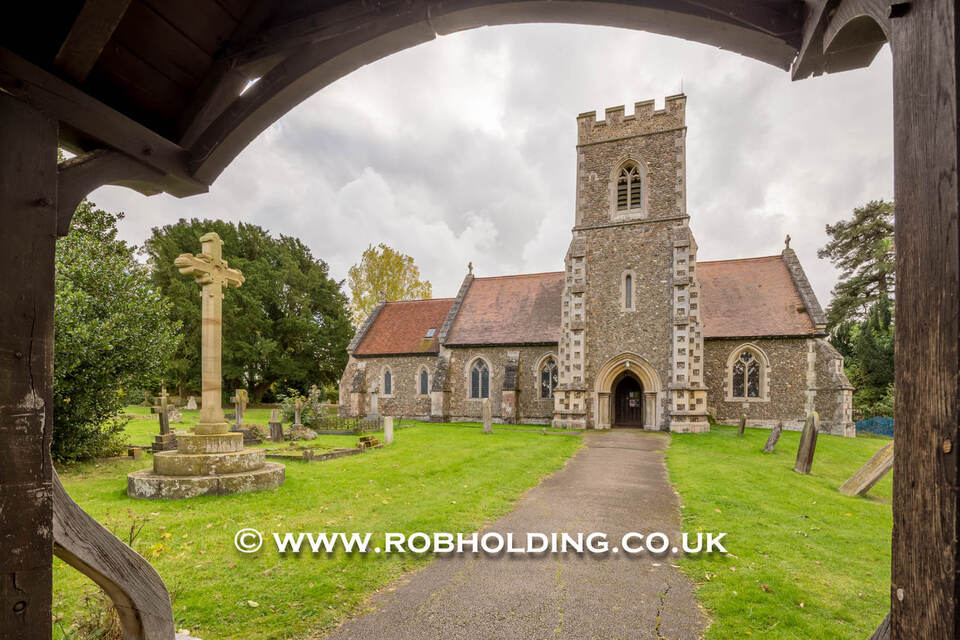 Exterior of a stone parish church seen through an archway
