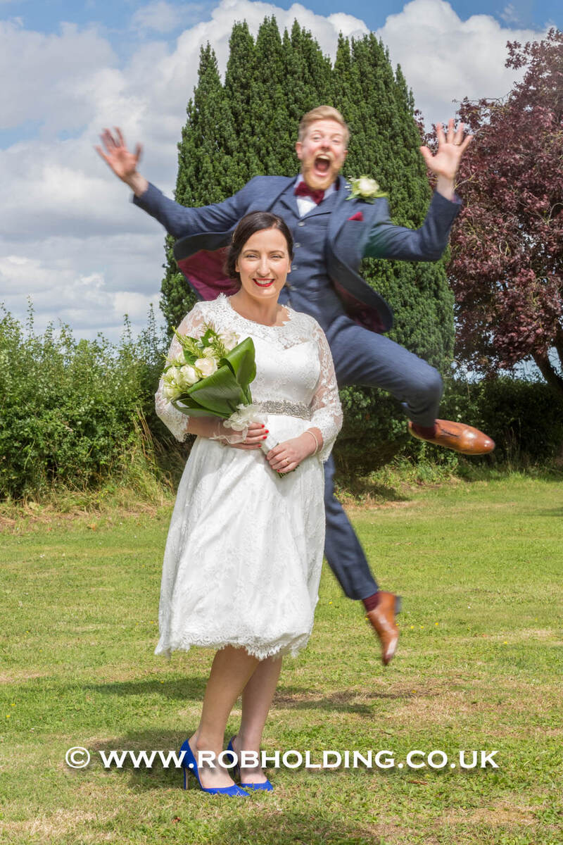 Groom leaping playfully beside the bride outdoors