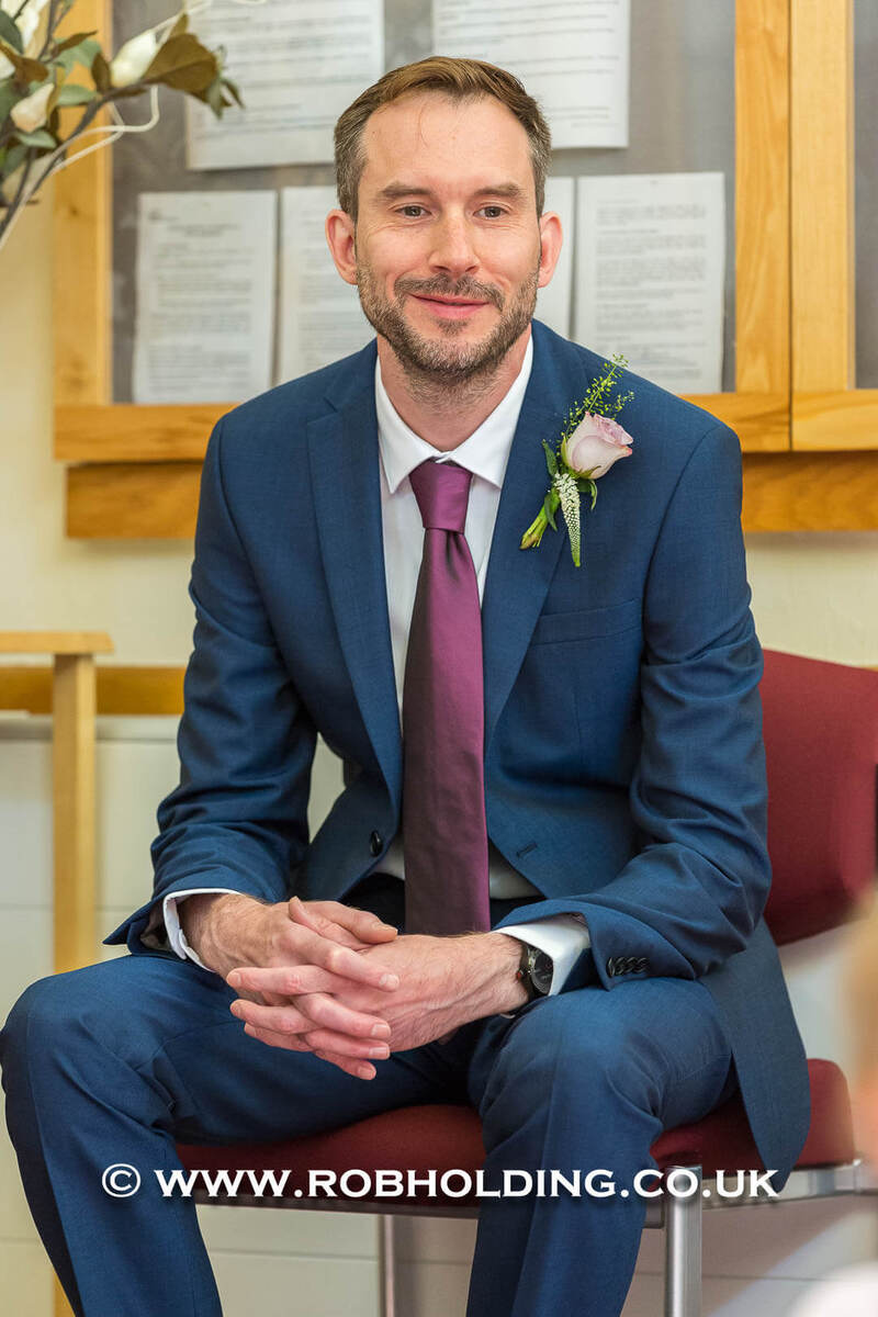 Portrait of a man in a navy suit with a pink boutonniere