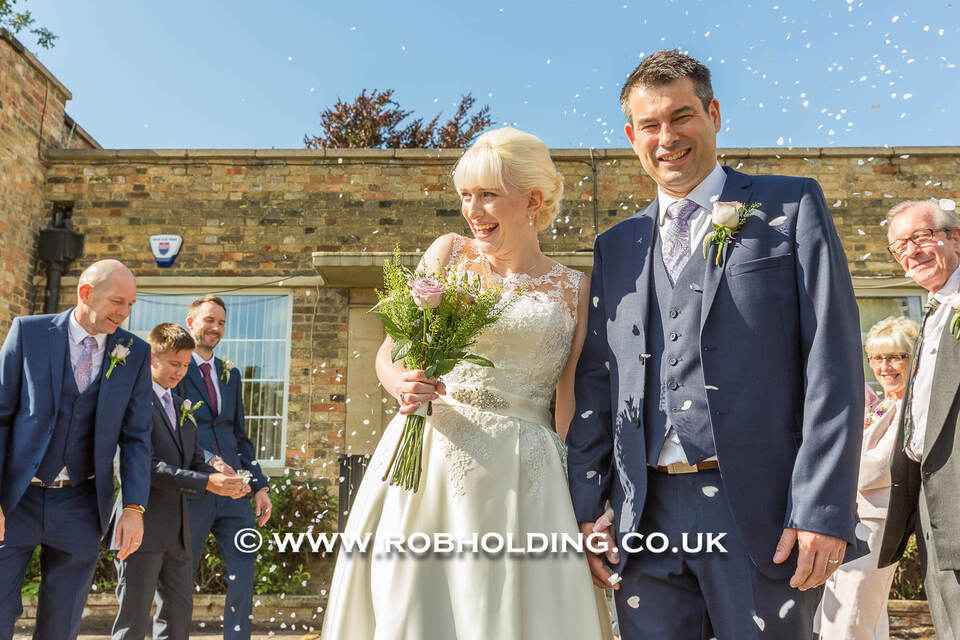 Bride and groom standing outdoors as confetti falls