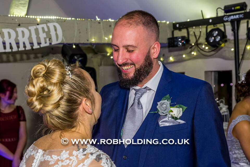 Groom and bride smiling closely under "Married" balloon letters