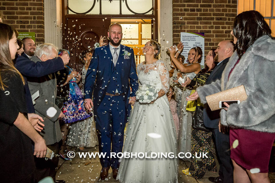 Bride and groom walking through confetti as they exit the venue